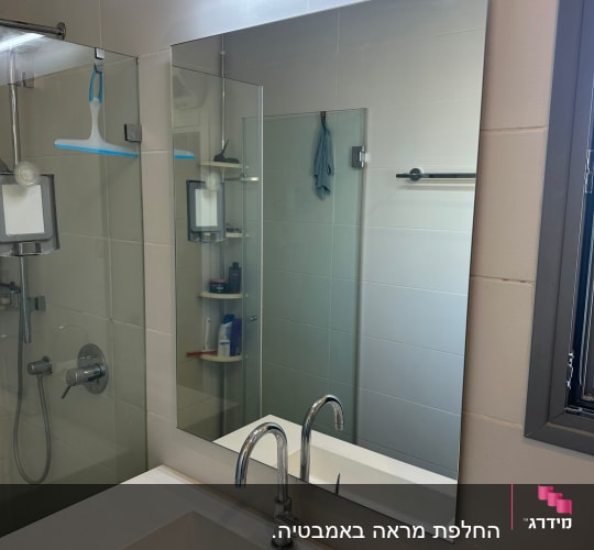 מראה מלבנית גדולה ללא מסגרת המותקנת מעל כיור בחדר רחצה